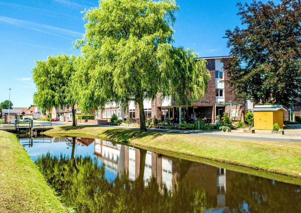 a river with trees and a building in the background at Hotel Hilling in Papenburg