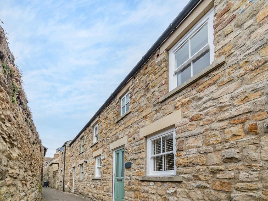 a stone building with white windows on a street at Raven Cottage in Barnard Castle