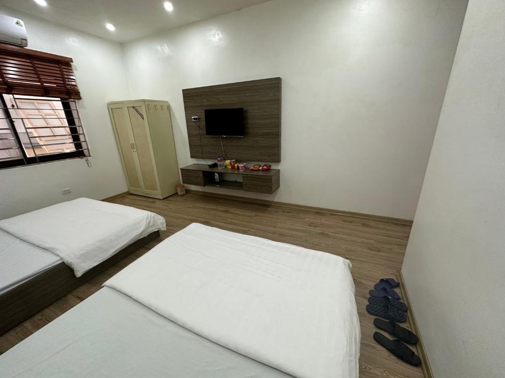 Dieses weiße Zimmer verfügt über 2 Betten und einen TV. in der Unterkunft Khách Sạn Thiên Hương - Thiên hương Hotel 