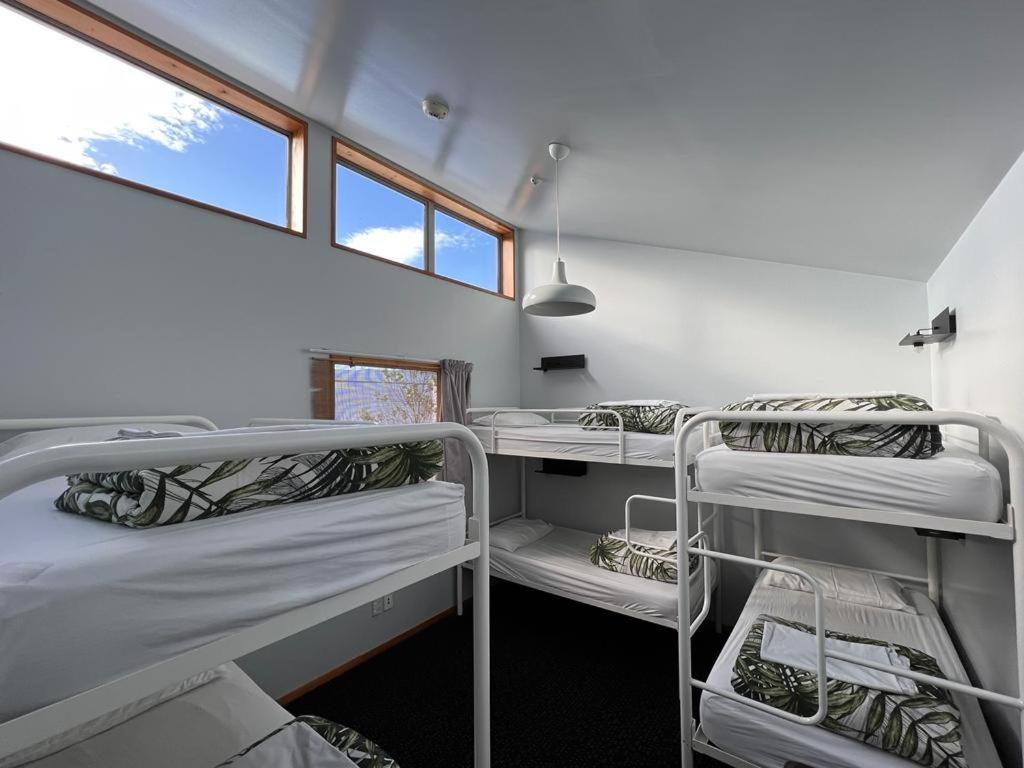 a room with three bunk beds and a window at On Top Backpackers in Dunedin