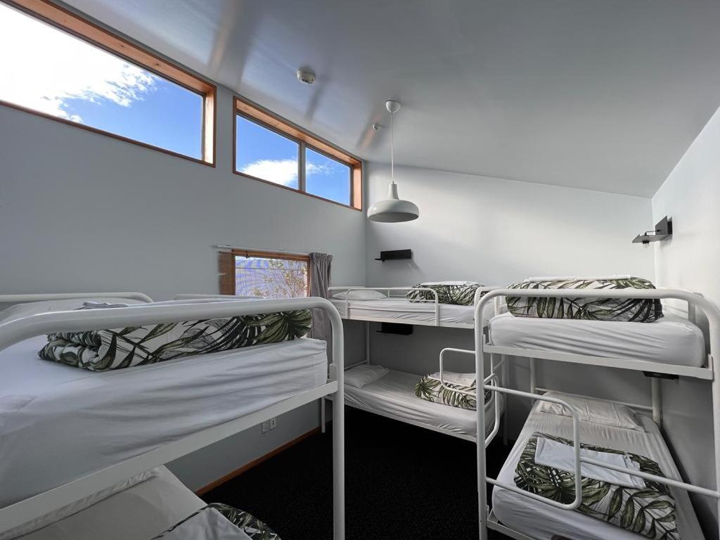 una stanza con tre letti a castello e una finestra di On Top Backpackers a Dunedin