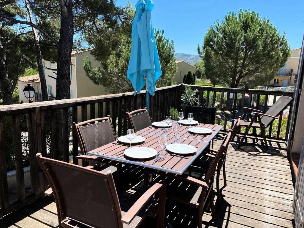 una mesa de madera con sillas y una sombrilla en una terraza en Les Coteaux de Pont Royal en Provence - maeva Home - Maison 4 pièces 6 pers 304, en Mallemort