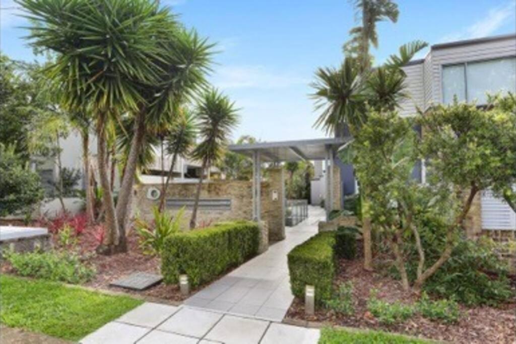 una casa con palmeras y una pasarela en Nor Easter Townhouse, en Caringbah