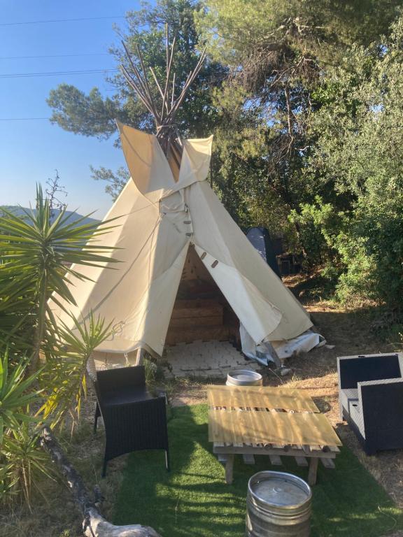 a tent with a table and chairs in a yard at Tipis La Paix retrouvée in Tourrette-Levens