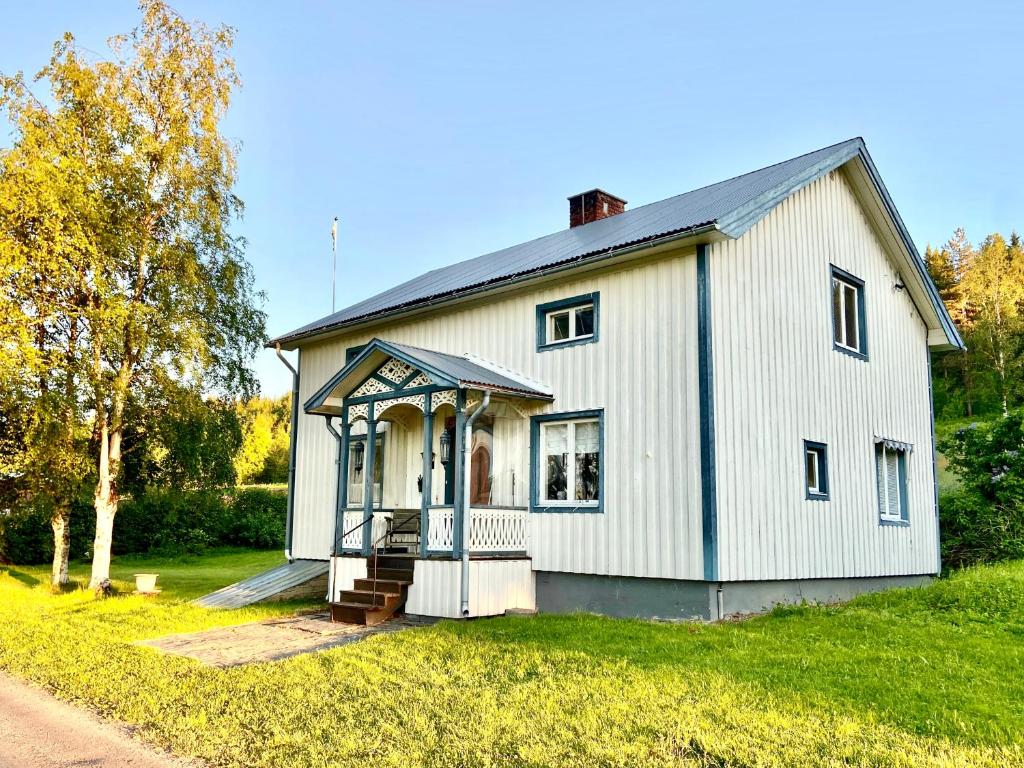 Casa blanca con porche en el césped en Vildmarksgård Lillviken en Strömsund