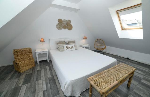 una camera da letto con un grande letto bianco e due tavoli di Retour de plage a Locmaria