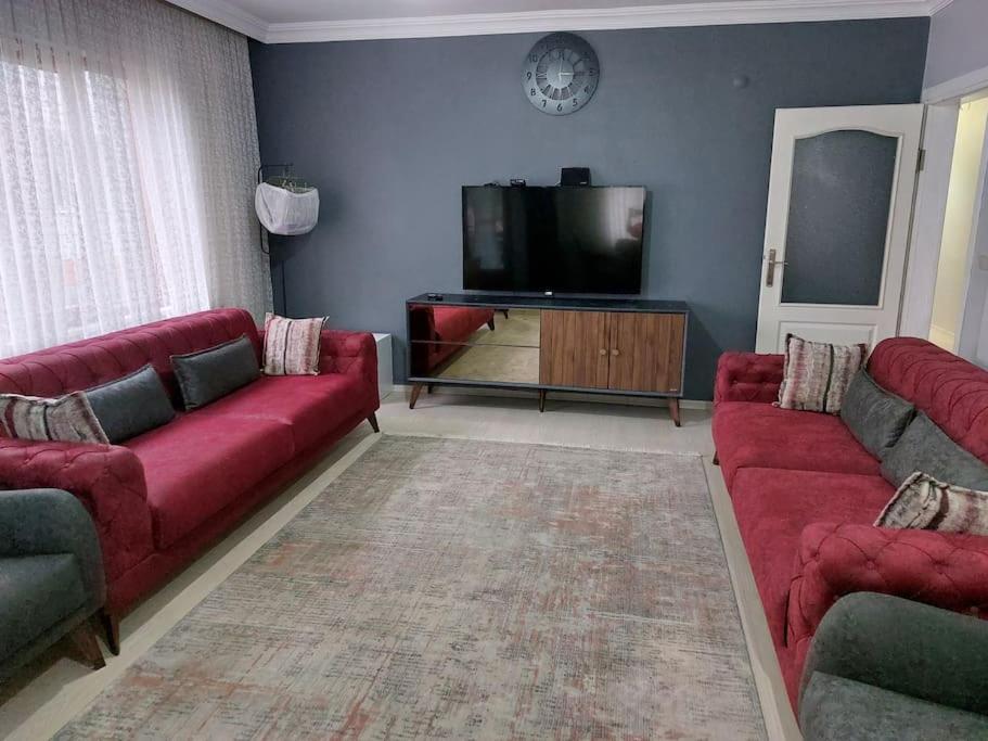 a living room with red couches and a flat screen tv at Rize , still close to the port in Cayeli