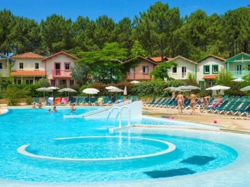 - une grande piscine avec des personnes assises sur la plage dans l'établissement Golf Sauvignon 13, à Lacanau