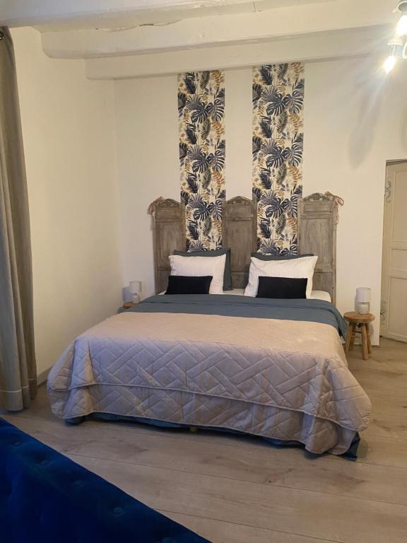 um quarto com uma cama grande com lençóis azuis e brancos em La Tuilerie em Verteuil-sur-Charente