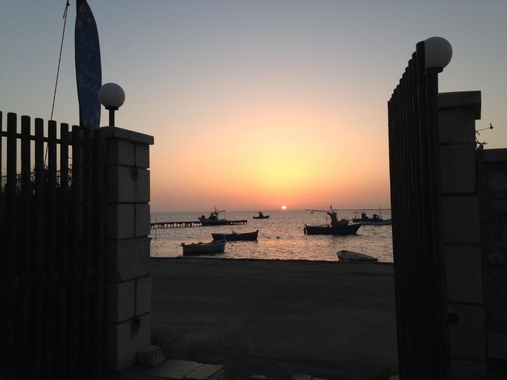 a sunset over a beach with boats in the water at Al Vecchio Pontile bed and breakfast in Marsala