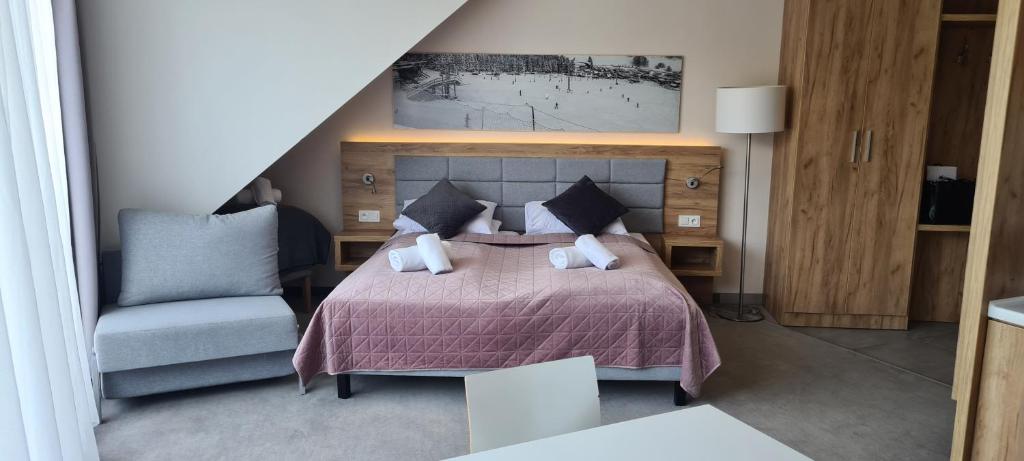 ein Schlafzimmer mit einem Bett und einem Stuhl in der Unterkunft Aparthotel Apartamenty Czarna Góra 403 in Heudorf