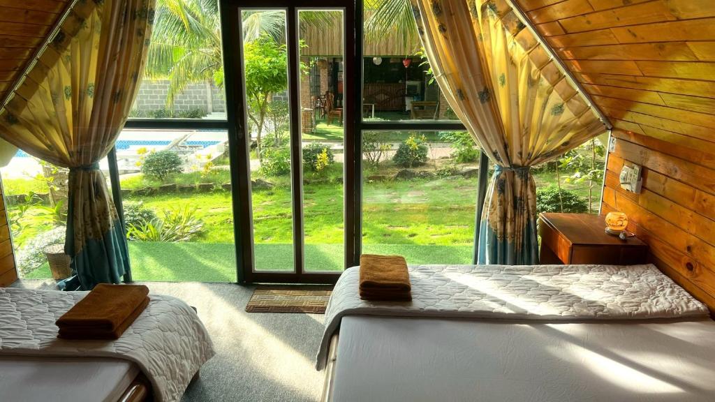 a bedroom with two beds and a large window at Phu Nam House - Resort in Phú Quốc