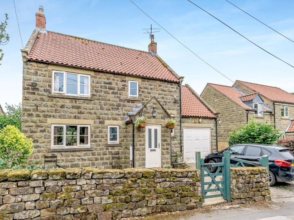 una casa in pietra con un muro di pietra e una macchina parcheggiata di fronte di Crown Gardens a Rosedale Abbey