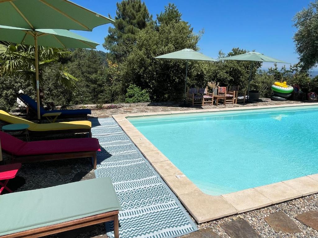 a swimming pool with chairs and umbrellas next to it at Le Planzollais in Planzolles