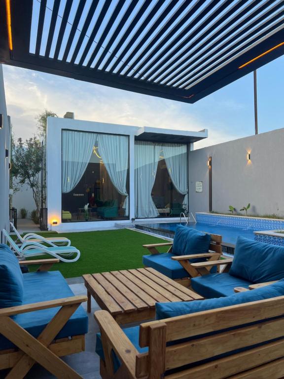 a patio with wooden furniture and a green lawn at شاليهات كورال بارك in Al Kura