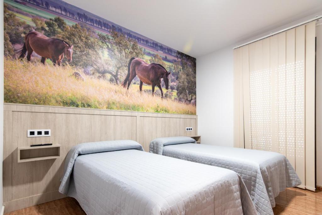 2 camas en una habitación con un cuadro en la pared en Hostal Viñuela en San Pedro de Mérida