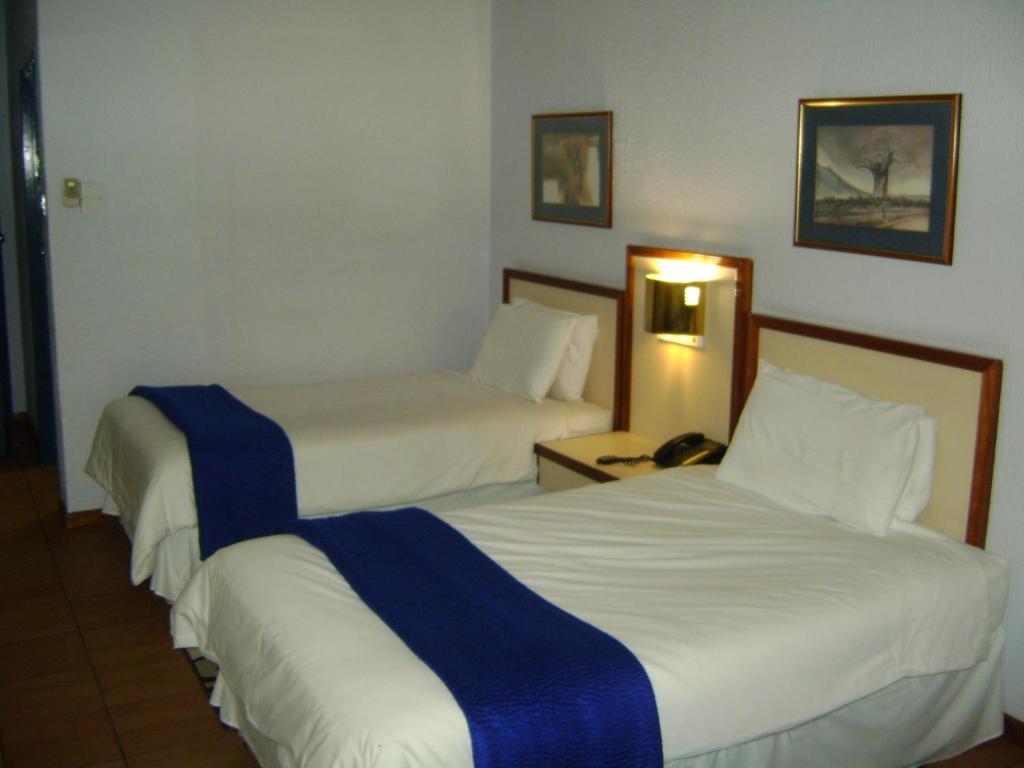 a hotel room with two beds and a telephone at Gaborone Hotel in Gaborone