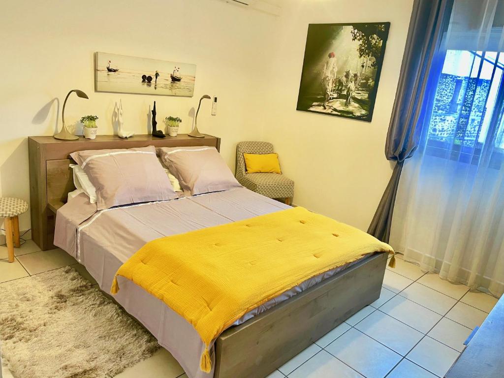 a bedroom with a bed with a yellow blanket on it at Kazalena in Saint-Pierre