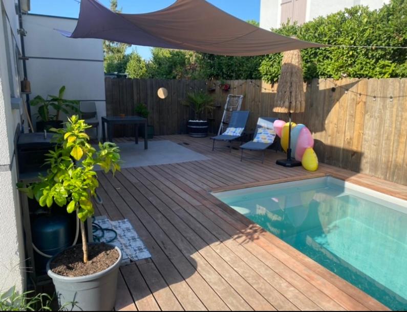 a backyard with a swimming pool and a wooden deck at Maison, piscine centreville Gujan-Mestras 4 hôtes in Gujan-Mestras
