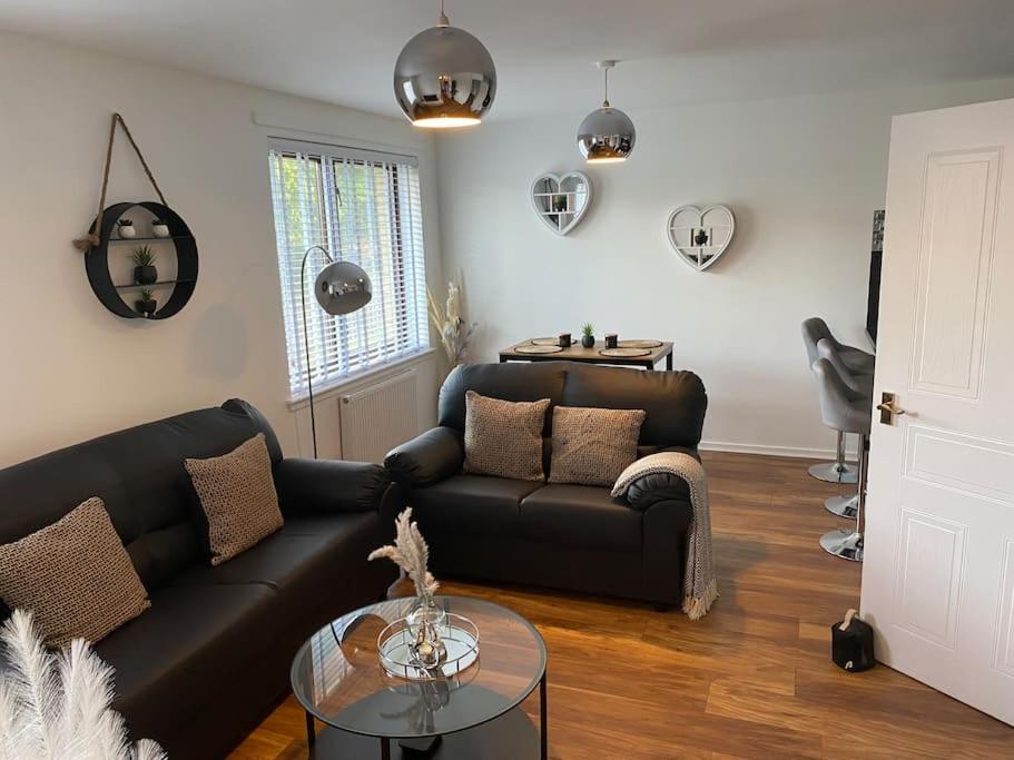 a living room with a black couch and a table at Perfectly situated luxury 2 bedroom apartment in Glasgow