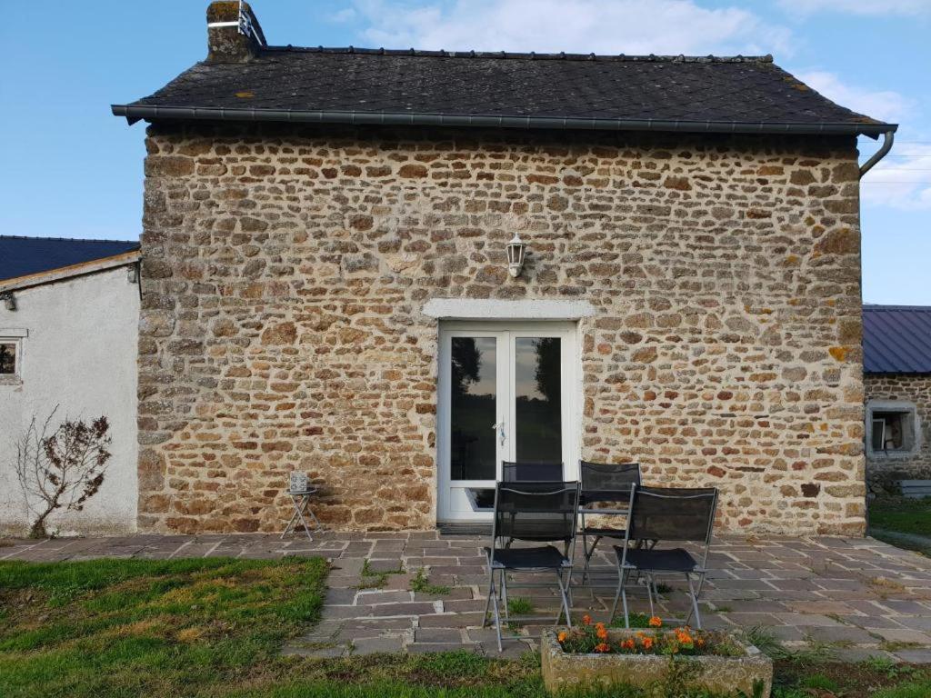 un bâtiment en briques avec deux chaises devant lui dans l'établissement Gîte à Romagné, à Romagné