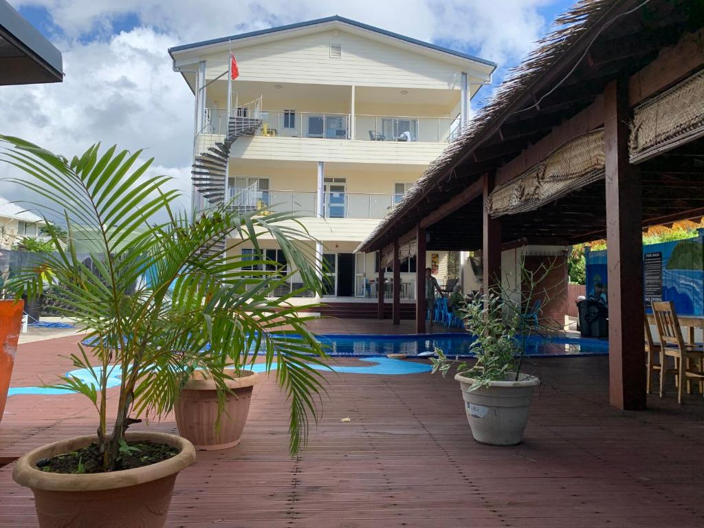 a building with potted plants next to a swimming pool at Alec's Hotel in Apia