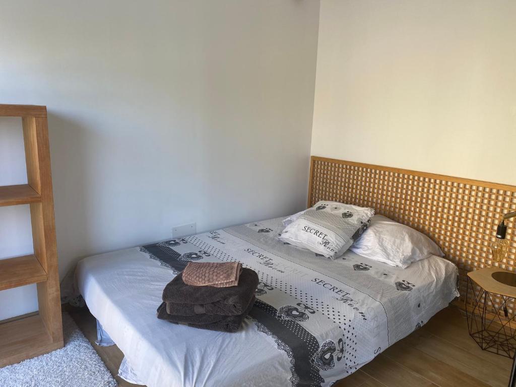 um pequeno quarto com uma cama e uma cabeceira em madeira em Nuit de charme & Spa em Lorgues