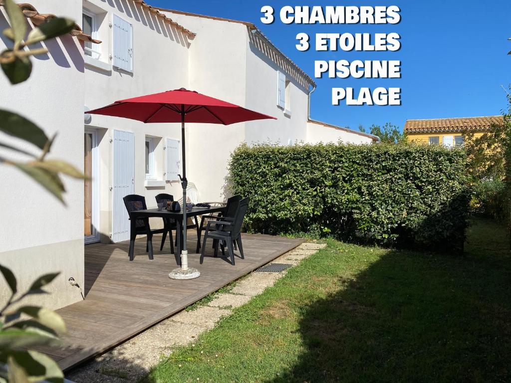 een patio met een tafel en stoelen en een parasol bij Le Village des Amareyeurs - Ile d'Oléron - Maison classée 3 étoiles avec piscine in Le Château-dʼOléron