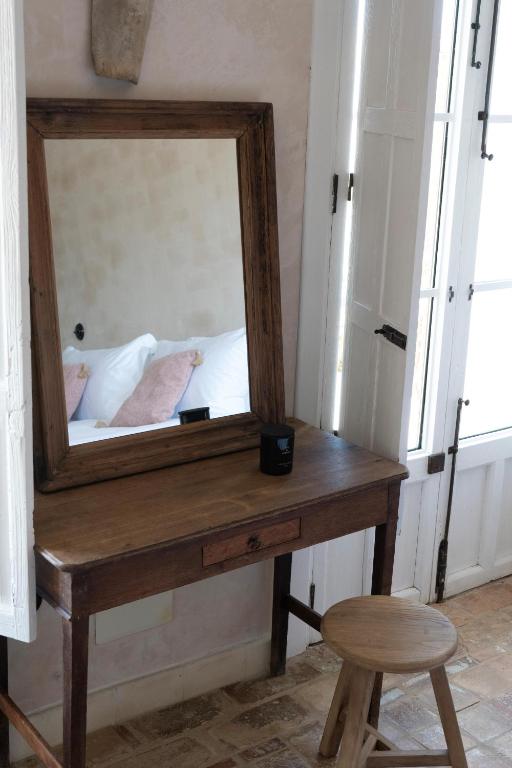 a mirror on a wooden table with a stool at Casa La Siesta in Vejer de la Frontera