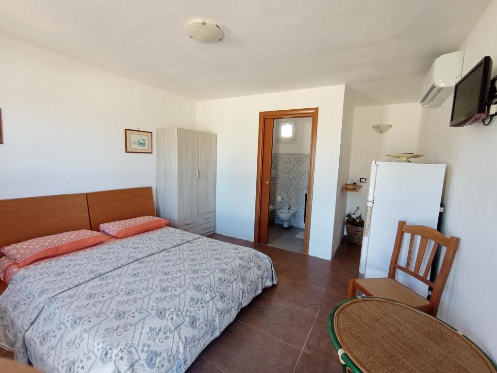 a bedroom with a bed and a chair and a refrigerator at Stanze Agli Ulivi in Porto Cesareo