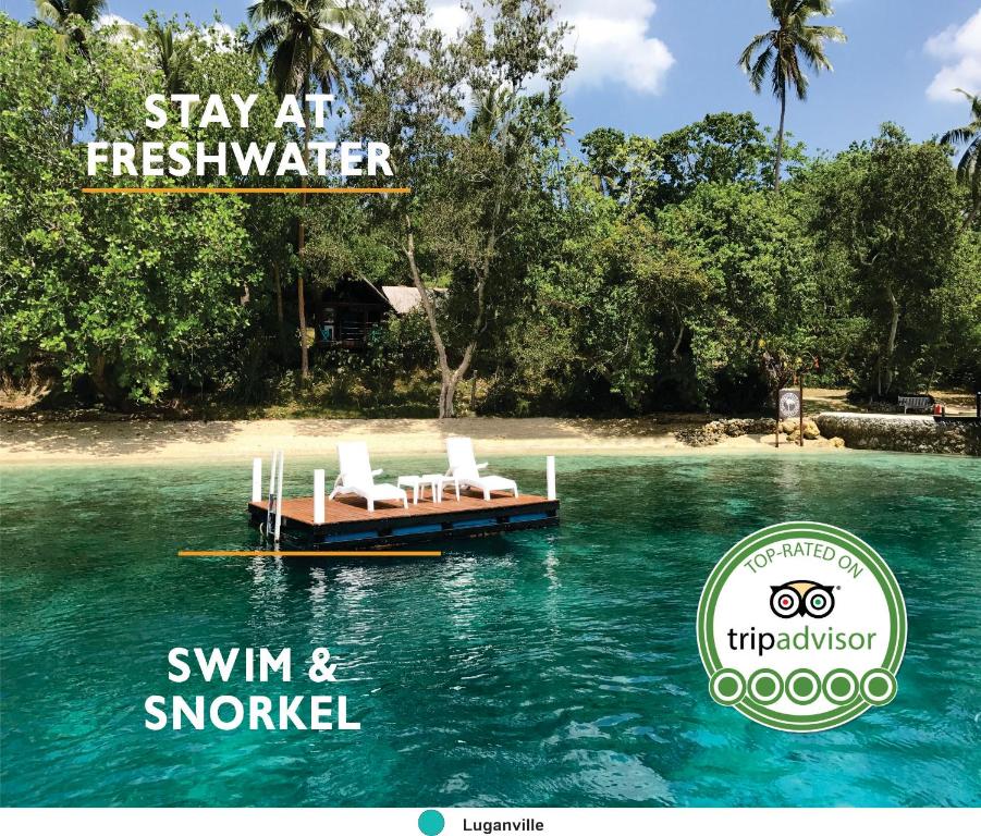 a dock in the water with two chairs and a beach at Freshwater Private Resort in Luganville