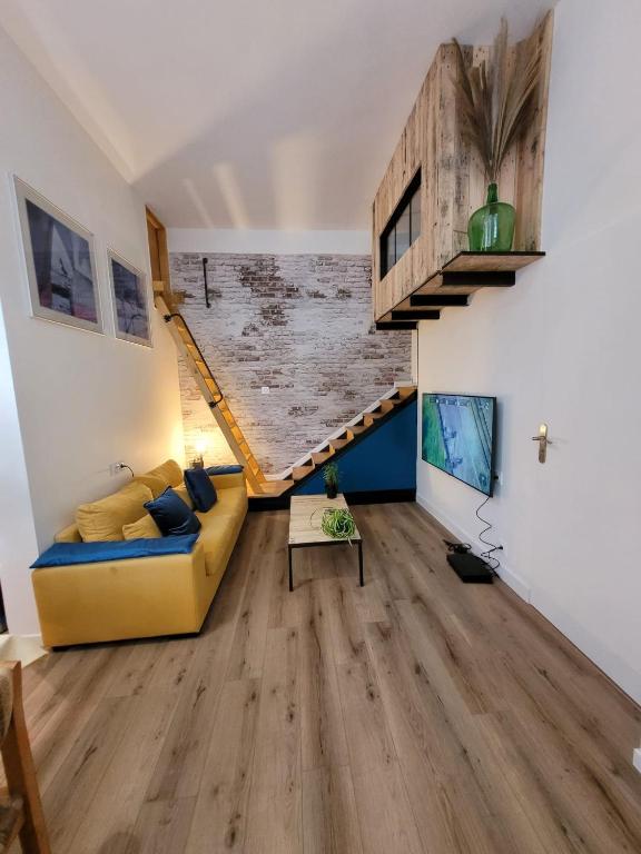 - un salon avec un canapé jaune et du parquet dans l'établissement Studio des Halles, au Havre