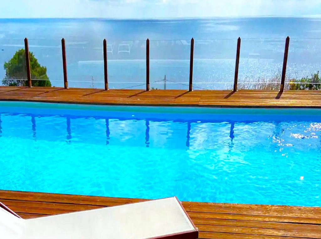 een zwembad met blauw water en een houten pier bij Il Casale San Vito in San Vito lo Capo