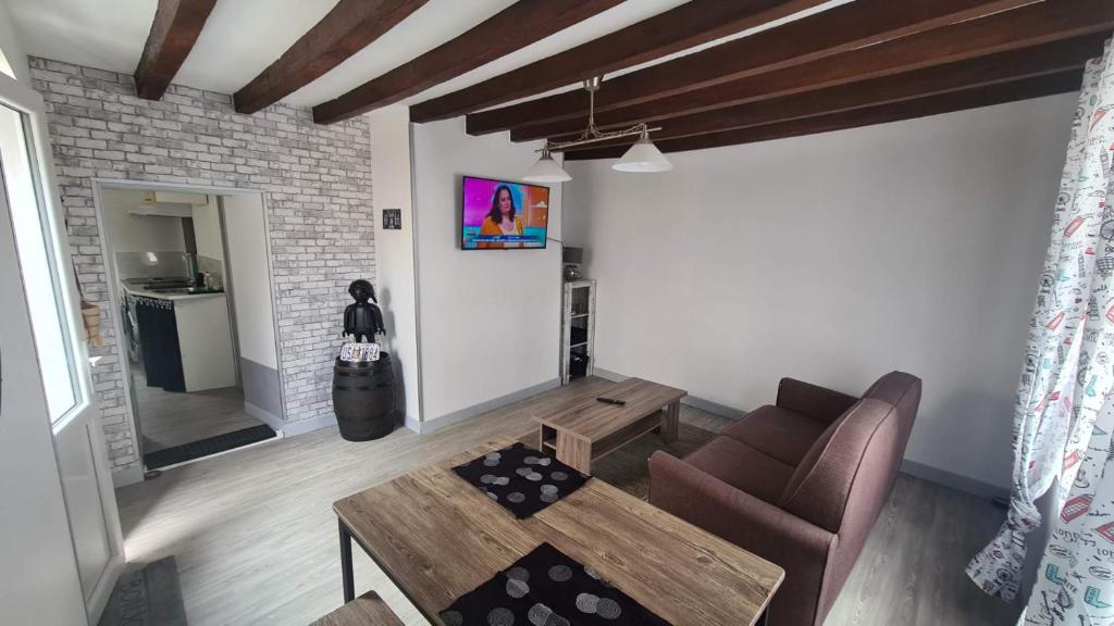 ein Wohnzimmer mit einem Sofa und einem Tisch in der Unterkunft Petite maison cosy wifi avec terrasse in Montigny-le-Gannelon