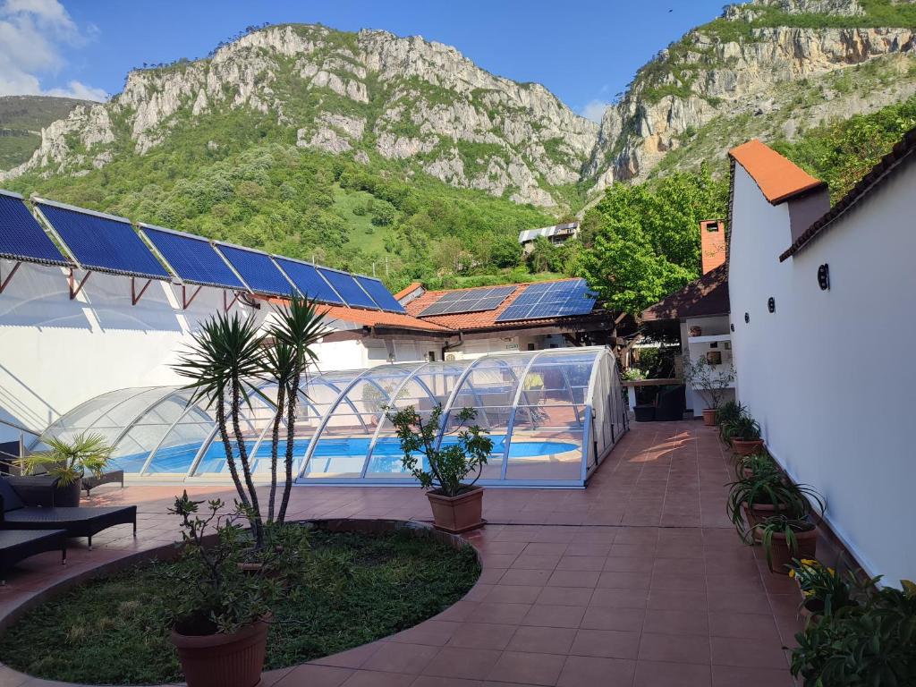 a building with a pool with a mountain in the background at Pensiunea La Dolce Vita in Băile Herculane