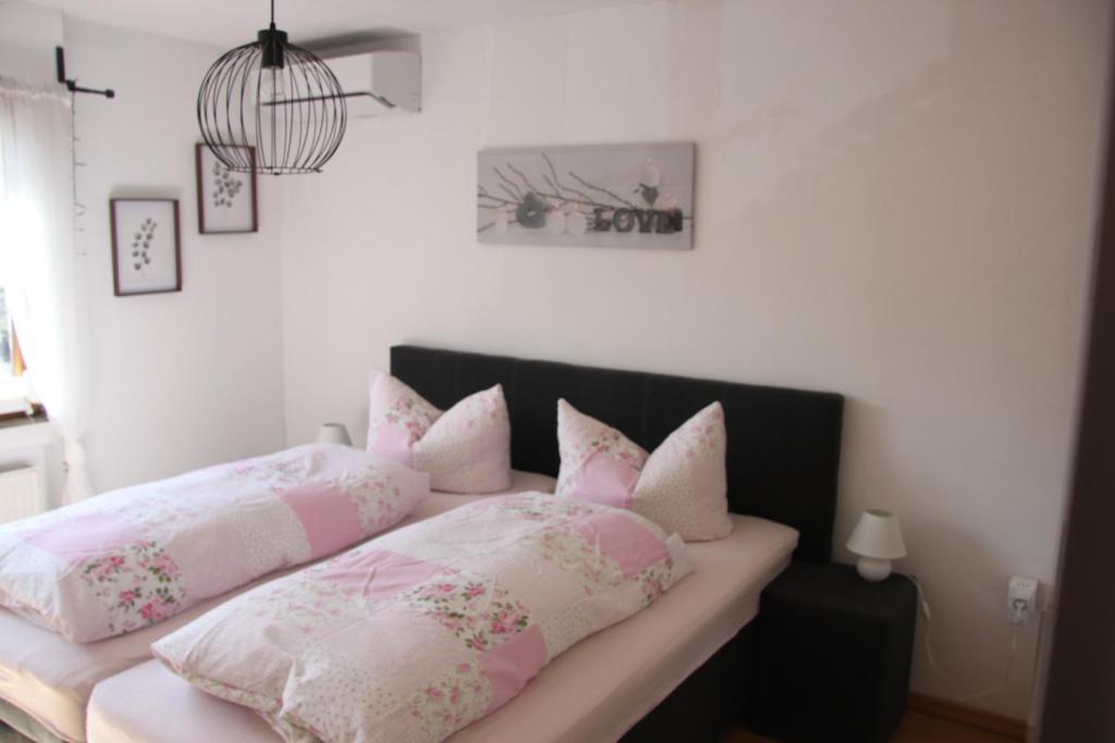una camera da letto con un letto con cuscini rosa e bianchi di Fewo Weinland a Zweibrücken