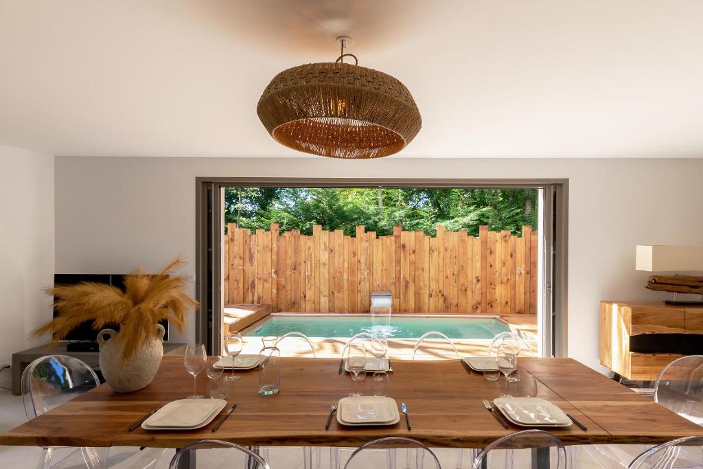una sala da pranzo con tavolo e piscina di Villa de luxe au Pyla avec piscine en bordure du golf d'Arcachon, 5 chambres a La Teste-de-Buch