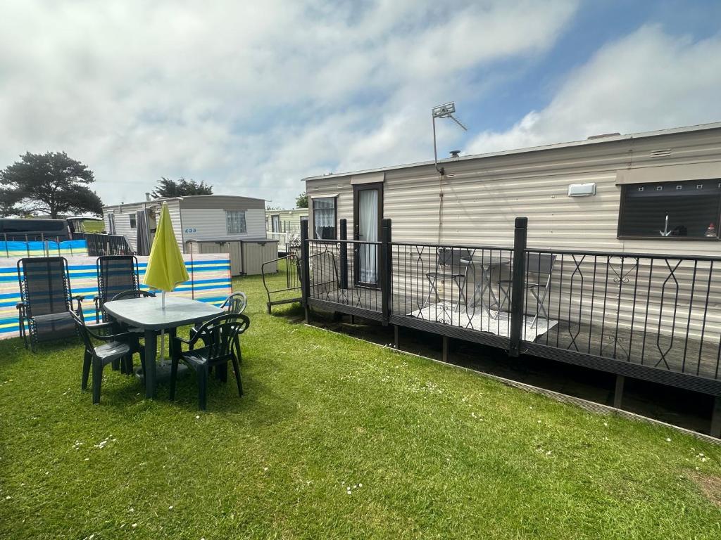 a patio with a table and chairs and a trailer at Tracy’s holiday home - static caravan in Hemsby