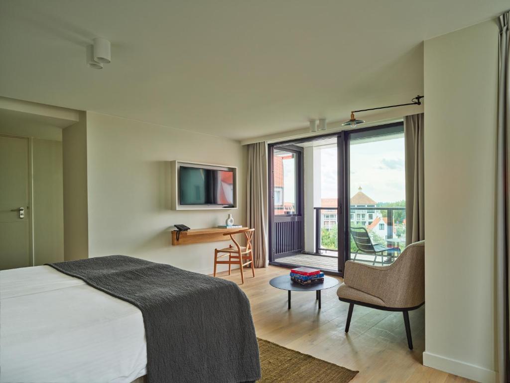 une chambre avec un lit, un bureau et une télévision dans l'établissement Hotel de Blanke Top, à Cadzand-Bad