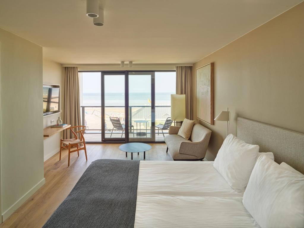 une chambre d'hôtel avec un lit et une vue sur l'océan dans l'établissement Hotel de Blanke Top, à Cadzand-Bad