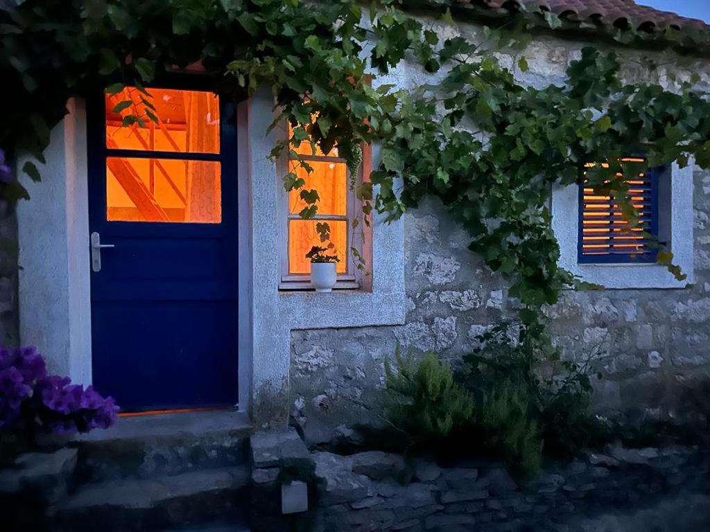una casa con una puerta azul y dos ventanas en Villa rustica bougainvillea, en Maslinica