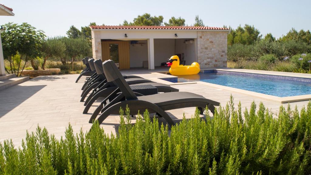 a pool with chairs and a rubber duck next to a house at Luxury Villa Nature with heated private pool, sauna & fire pit, a short walk to the beach in Milna