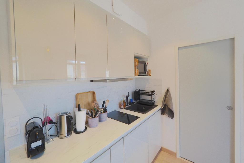 a kitchen with white cabinets and a counter top at Studio refait à neuf en hypercentre avec balcon in Aix-les-Bains
