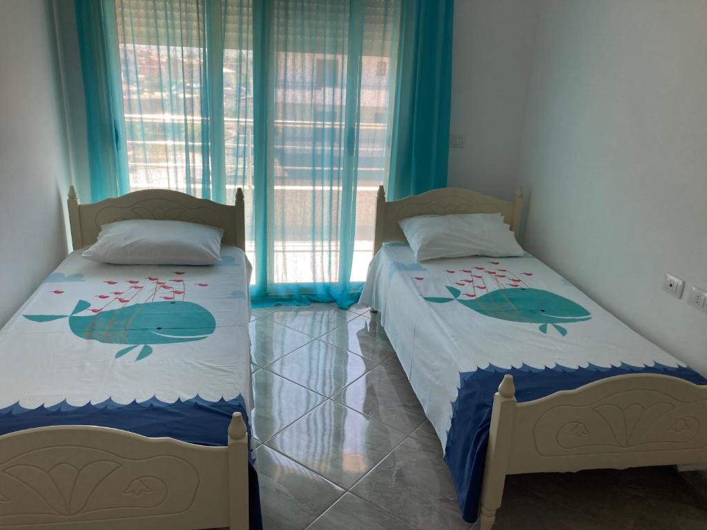 two beds in a room with blue curtains at Azure beach apartment in Orikum