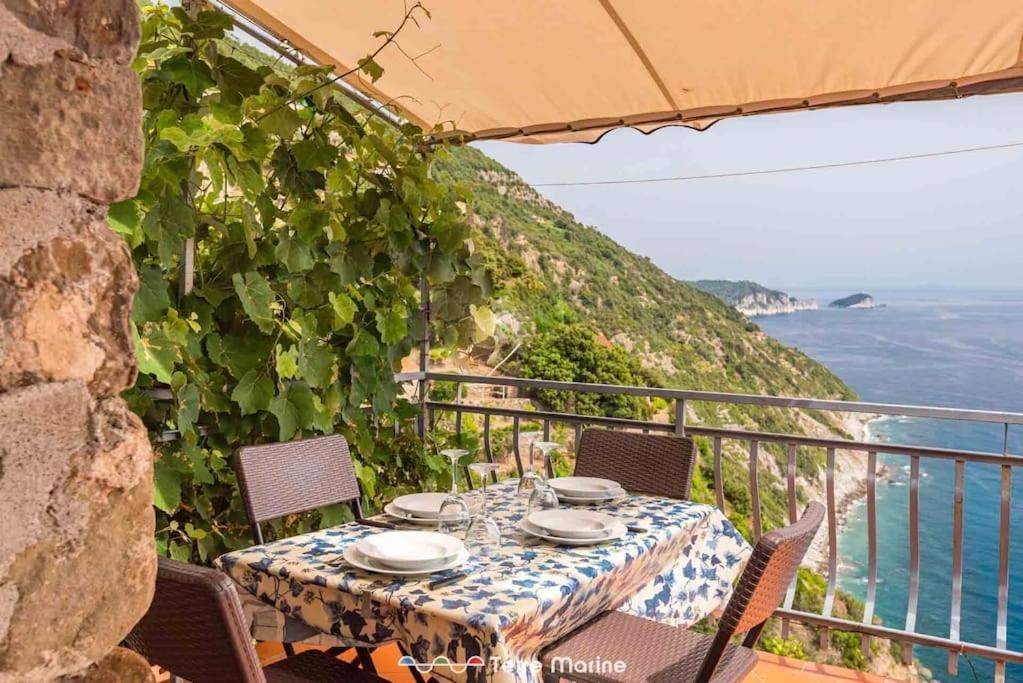 a table on a balcony with a view of the ocean at Casa Giulia, Trekking and Nature in Campiglia