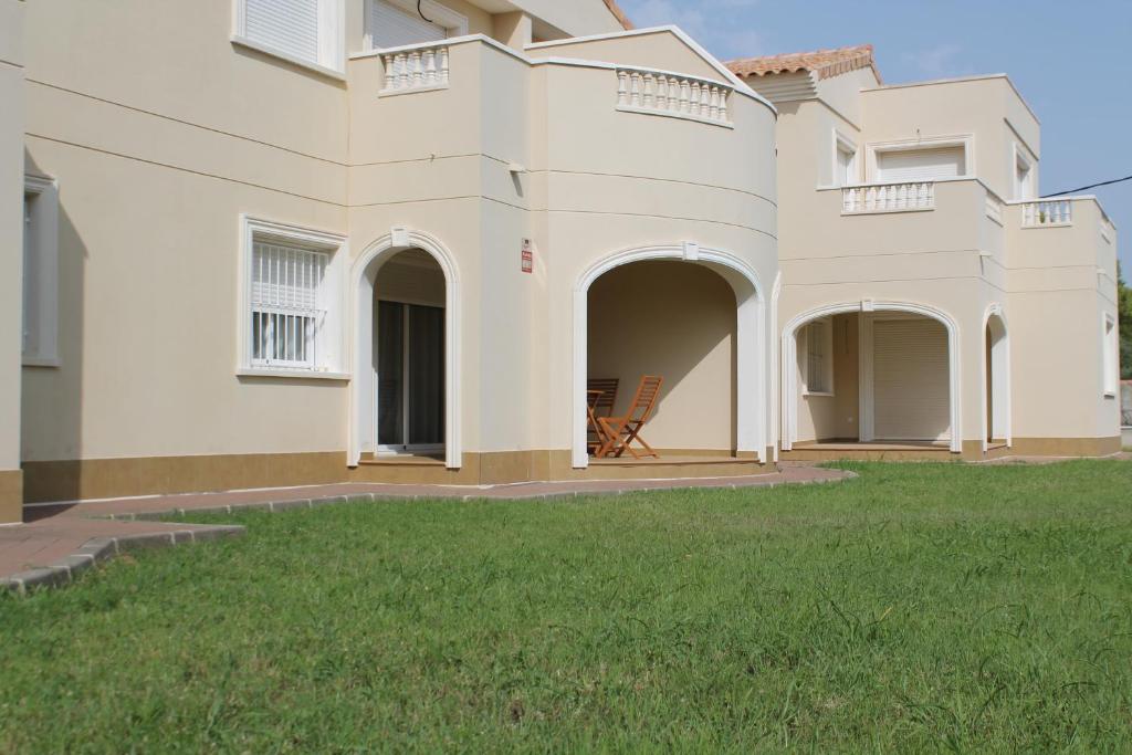 a large white house with a lawn in front of it at Apartamento nuevo en urbanización a 250 metros de la playa in Denia