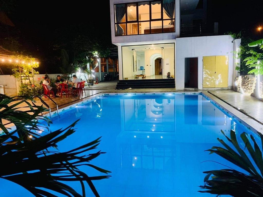 a large blue swimming pool in front of a house at Phong Nha Moonlight Villas in Phong Nha