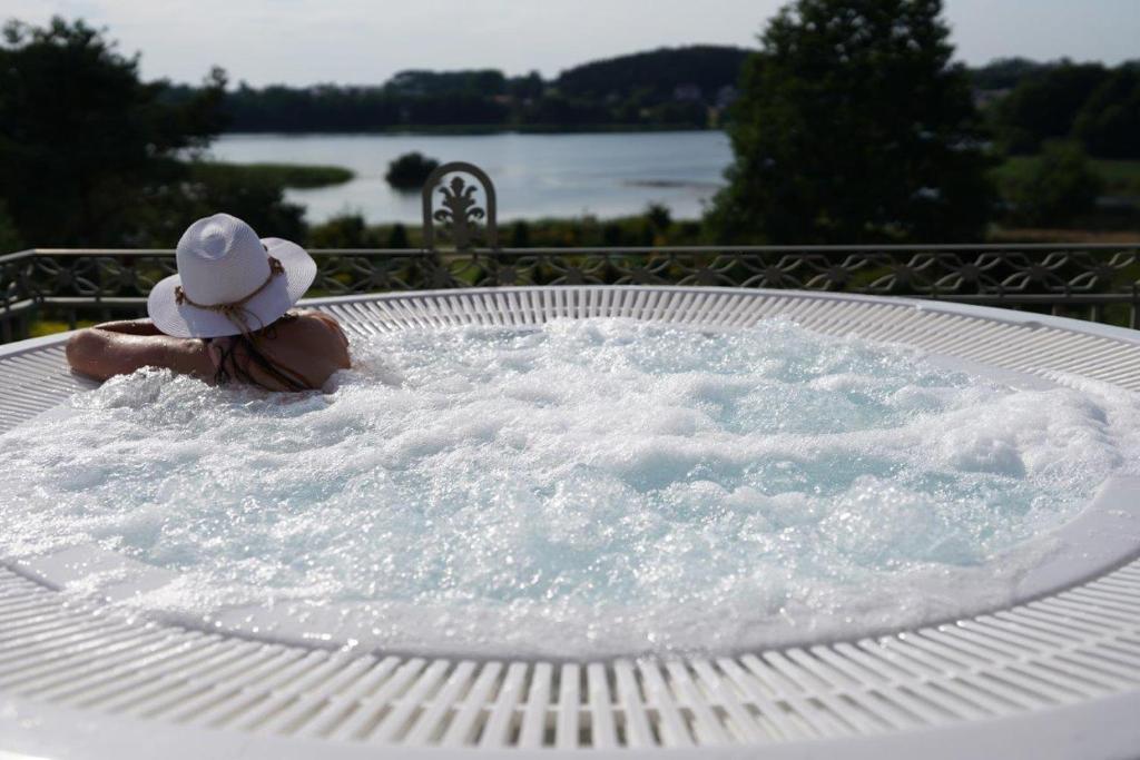 une femme dans un bain à remous avec un chapeau dans l'établissement Dom Wczasowy Stenka, à Gowidlino