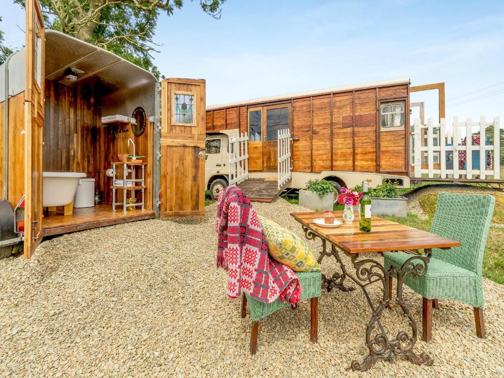 an rv with a table and chairs in a yard at Dennis in Llanwnda