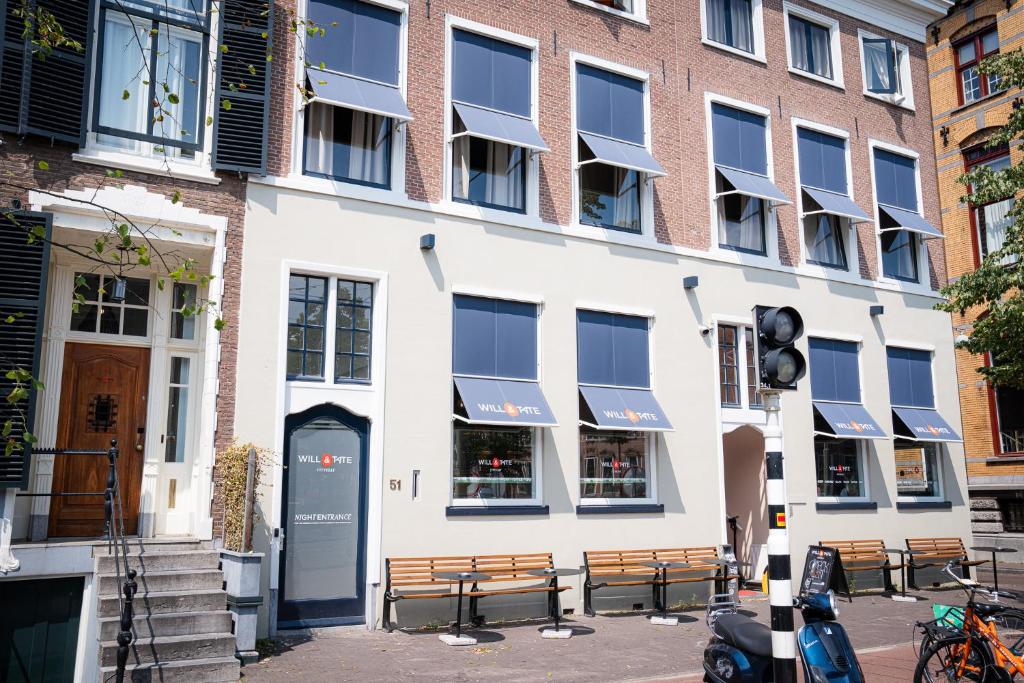 ein weißes Gebäude mit Bänken davor in der Unterkunft Will & Tate City Stay in Den Haag